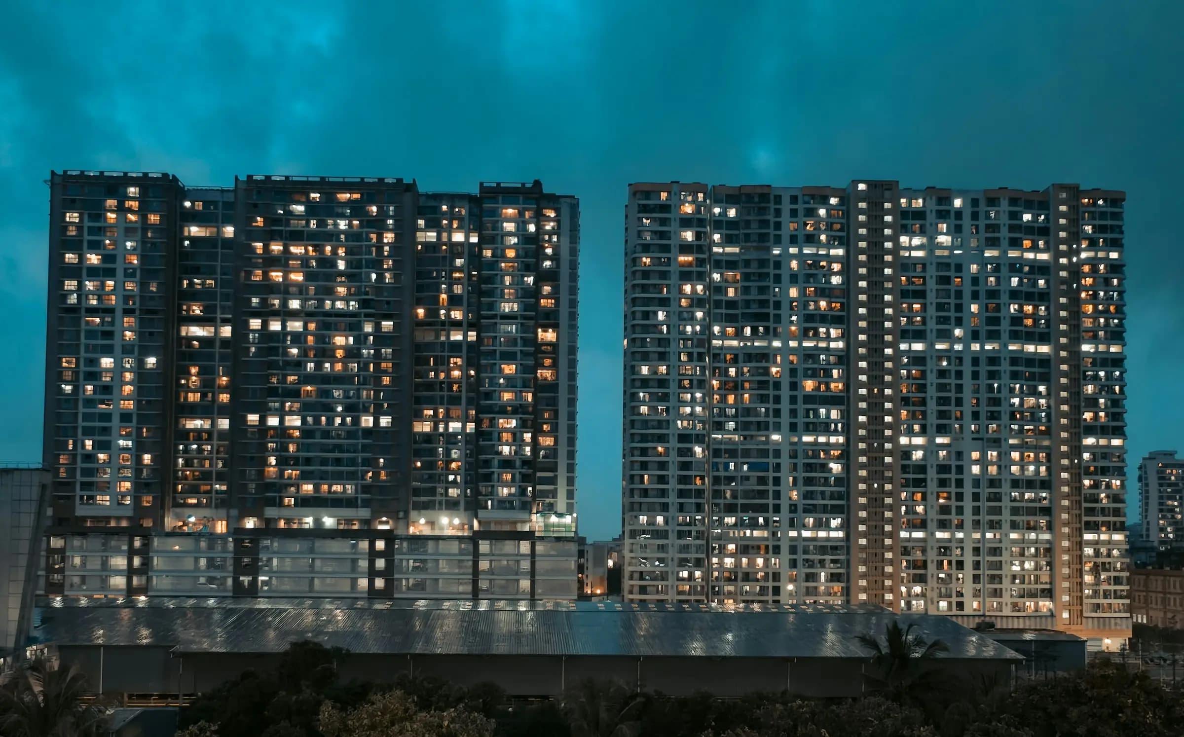 Two residential high-rises with lit windows at dusk
